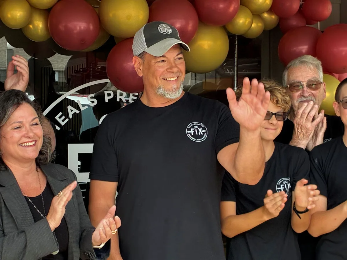 Chef T waving to applause at The Fix's storefront ribbon-cutting celebration